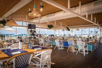 a restaurant with tables and chairs and windows at htop Olympic #htopEnjoy in Calella