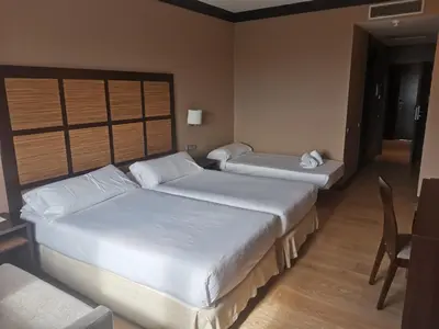 two beds in a hotel room with a table and chairs at Aparthotel Attica 21 Vallés in Sabadell