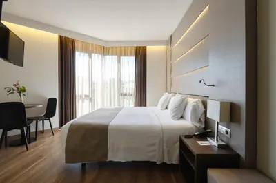 a hotel room with a bed and a desk and a table at Hotel America Barcelona in Barcelona
