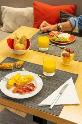 a table with a plate of food and orange juice at Hotel America Barcelona in Barcelona