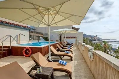 a resort with a swimming pool and chairs and an umbrella at Sercotel Kalma Sitges in Sitges