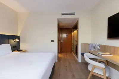 a hotel room with a bed and a desk and a tv at Sercotel Kalma Sitges in Sitges