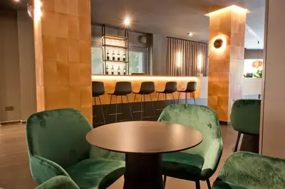 a waiting room with green chairs and a table at Aparthotel Atenea Valles in Granollers