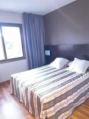 a bedroom with a bed with a striped blanket on it at Hotel Bruc in El Bruc