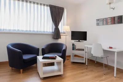 a living room with two chairs and a desk and a tv at Aparthotel Atenea Barcelona in Barcelona