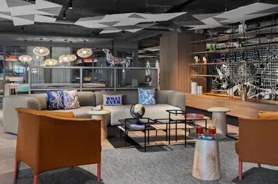 a living room with a couch and tables and chairs at Moxy Barcelona in Barcelona