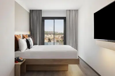 a bedroom with a large bed and a flat screen tv at Moxy Barcelona in Barcelona