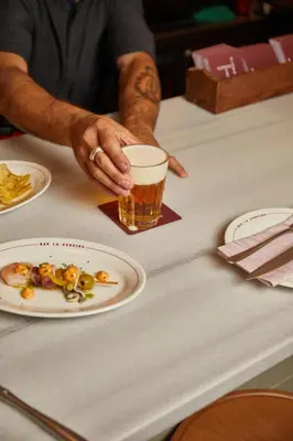 a man sitting at a table with a glass of beer at Hotel Regina Barcelona in Barcelona
