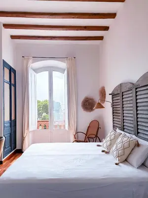 a white bedroom with a large bed and a window at Hotel Palou 1874 in Sant Pere de Ribes