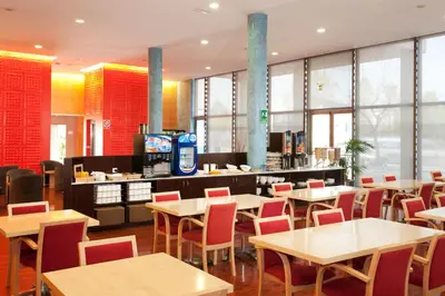 a restaurant with tables and chairs and a counter at Holiday Inn Express Molins de Rei by IHG in Molins de Rei