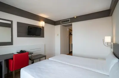 a bedroom with a bed and a desk and a television at Medplaya Hotel Santa Monica in Calella