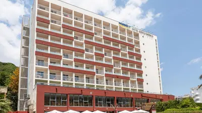 a tall white building with a red building at Medplaya Hotel Santa Monica in Calella