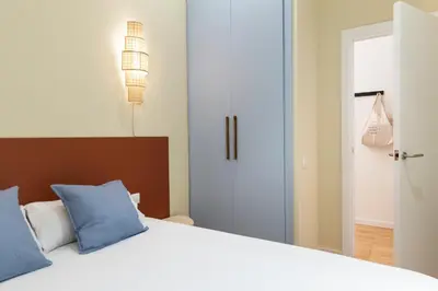 a bedroom with a white bed with blue pillows at Señor Urgell Apartment by Olala Homes in Barcelona