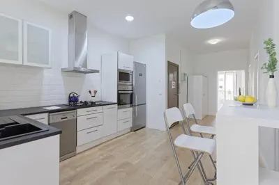 a white kitchen with white cabinets and a table and chairs at CENTRAL & BRIGHT APARTMENT!! in Barcelona