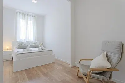 a white bedroom with a bed and a chair at CENTRAL & BRIGHT APARTMENT!! in Barcelona