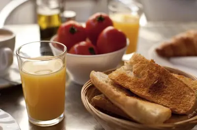 a bowl of bread and a glass of orange juice and a bowl of fruit at Hotel Ciutat De Sant Adria in Sant Adria de Besos