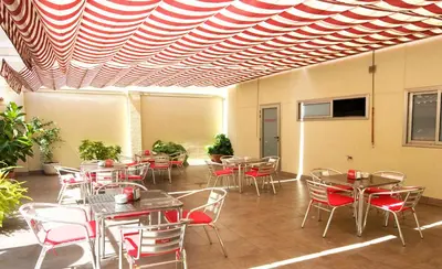 a dining room with tables and chairs under a striped ceiling at Hotel Ciutat De Sant Adria in Sant Adria de Besos