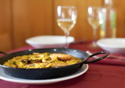 a pan of food on a table with glasses of wine at Hotel Ciutat De Sant Adria in Sant Adria de Besos