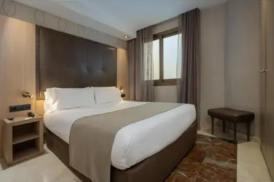 a bedroom with a white bed and a brick wall at Gran Hotel Barcino 4 Estrellas SUPERIOR in Barcelona
