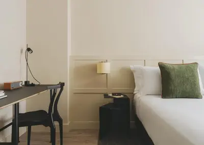 a bedroom with a desk and a bed with a green pillow at Catalonia Boulevard in Barcelona