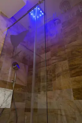 a glass shower in a room with a wooden floor at Flor Parks in Barcelona