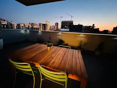 a wooden table and chairs on a balcony with a city skyline at Beach & Culture Barcelona Port Forum Penthouse Apartment in Sant Adria de Besos