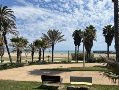 a park with two benches and palm trees and the beach at Beach & Culture Barcelona Port Forum Penthouse Apartment in Sant Adria de Besos