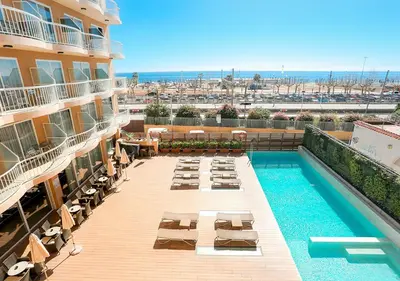 an outdoor swimming pool with chaise lounges and a hotel at KAKTUS Hotel Volga in Calella