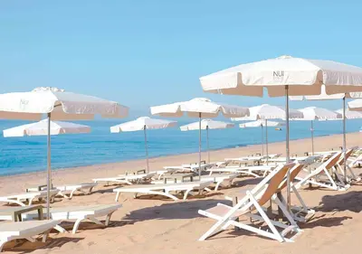 a bunch of chairs and umbrellas on a beach at KAKTUS Hotel Volga in Calella