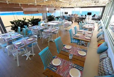 a restaurant with tables and chairs and the beach at KAKTUS Hotel Volga in Calella