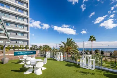 a row of white chairs on a lawn in front of a building at Occidental Atenea Mar - Adults Only in Barcelona