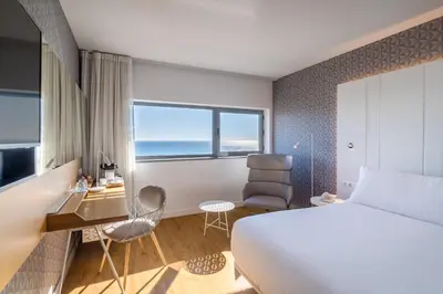 a hotel room with a bed and a desk and chair at Occidental Atenea Mar - Adults Only in Barcelona