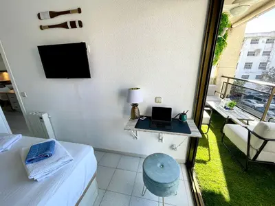 a room with a bed and a laptop on a table at Apartemento piscina centro calella 3 min playa in Calella