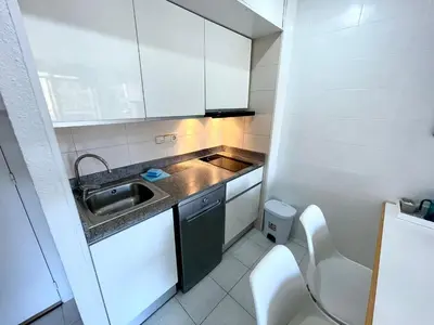 a small kitchen with white cabinets and a sink at Apartemento piscina centro calella 3 min playa in Calella