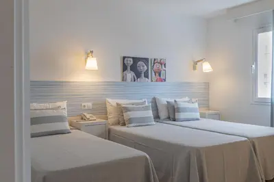 two beds in a hotel room with white sheets at FERGUS Club Pineda Splash in Pineda de Mar
