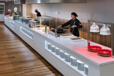 a woman standing in a kitchen preparing food at Hotel Oasis Park Splash in Calella
