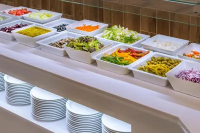 a buffet line with plates and bowls of vegetables at Hotel Oasis Park Splash in Calella