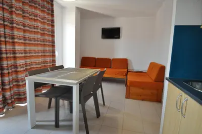 a kitchen with a table and chairs and a couch at Aparthotel Safari in Calella
