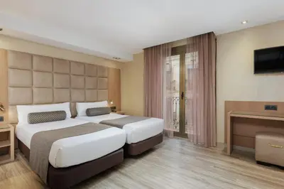 a hotel room with two beds and a television at Hotel Suizo in Barcelona