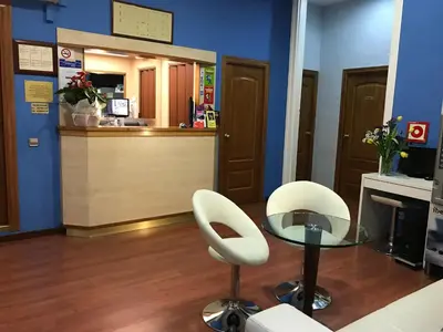a salon with two white chairs and a glass table at Hotel Pelayo in Barcelona