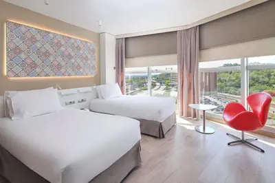 a hotel room with two beds and a red chair at Eurostars Don Cándido in Terrassa