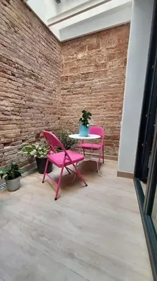 a pink table and chairs in a room with a brick wall at Acogedor apartamento con entrada independiente in Barcelona