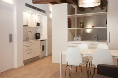 a kitchen and dining room with a table and white chairs at Habitat Apartments Alissia in Barcelona