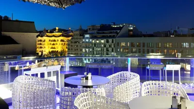 a table and chairs on a balcony at night at Hotel Condes de Barcelona in Barcelona