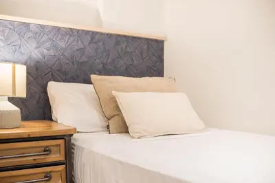 a bed with white sheets and pillows next to a table at Style and design in the best location, Eixample Barcelona in Barcelona