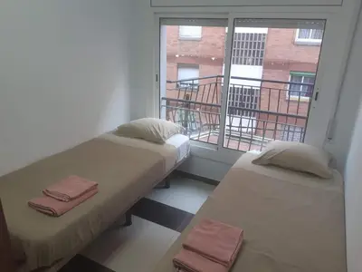 two beds sitting in a room with a window at Lucky House in Badalona
