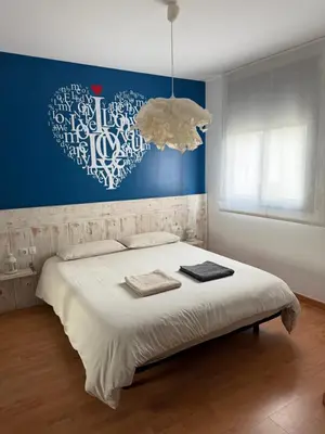 a bedroom with a large bed with a blue wall at La Llum de Sitges in Sitges
