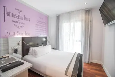 a bedroom with a large white bed and a desk at Petit Palace Boqueria Garden in Barcelona