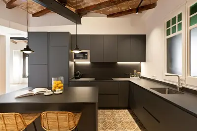 a kitchen with black cabinets and a table with fruit on it at Enjoy Apartments La Riera One in Barcelona
