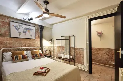 a bedroom with a bed and a brick wall at BBarcelona Parallel Apartment in Barcelona